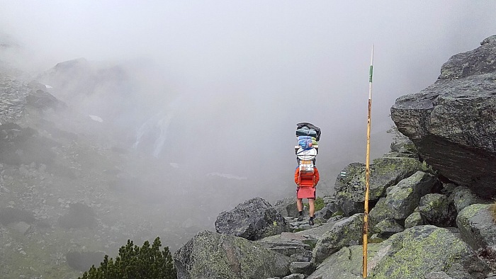 A man carrying food and supplies on a mountain path to the Tery Cabin in High Tatras.