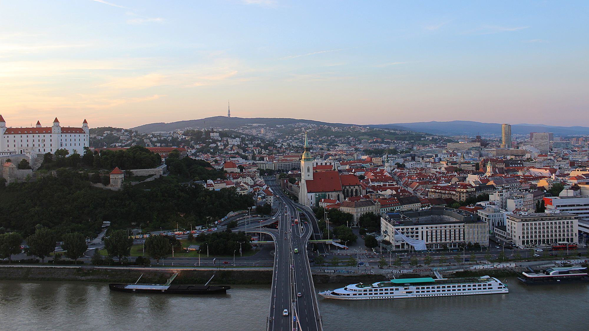 View from UFO Outlook tower over the bridge to the Old Town and Bratislava castle during sunset.